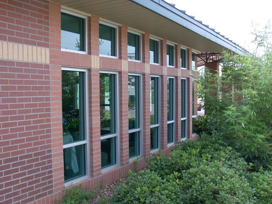 Brick medical building exterior with large windows and landscaping