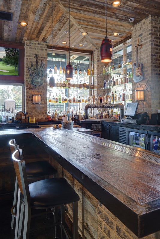 Rustic bar interior with exposed wood beams, brick walls, and pendant lighting